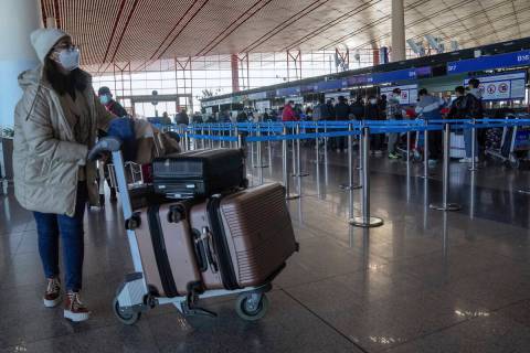 A masked traveler arrives at the international flight check in counter at the Beijing Capital I ...