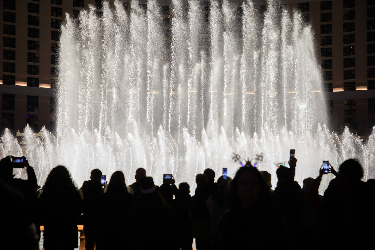 New Year’s Eve revelers watch the Bellagio fountain show the Strip on Saturday, Dec. 31, ...