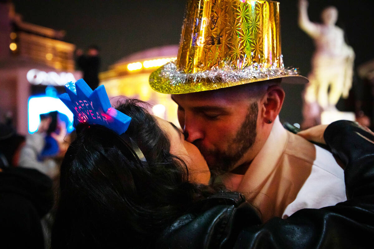 New Year’s Eve revelers, Wendy Flores, left, and Eric Oeser, right, share a New Year’s kiss ...