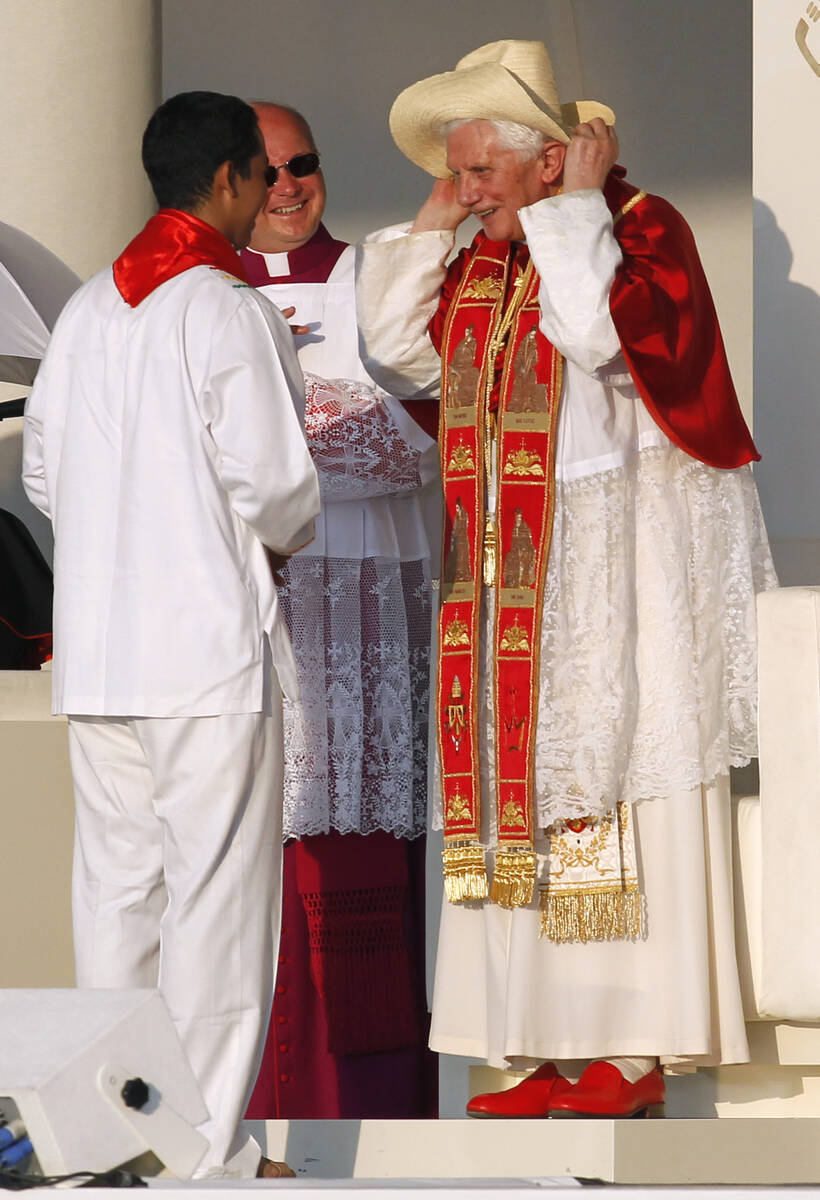 Pope Benedict XVI puts on a hat presented to him by a young man representing the youth from Lat ...