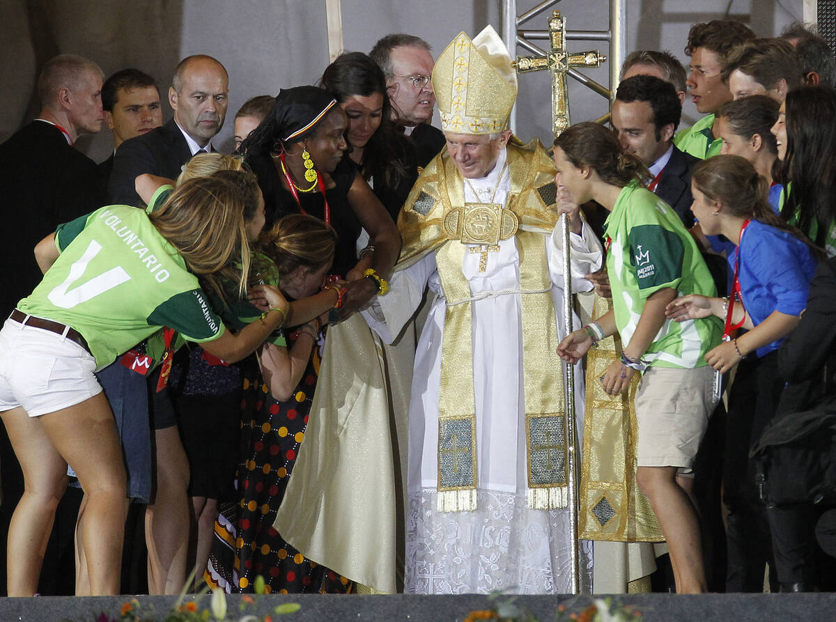 Pilgrims react as they approach Pope Benedict XVI and kiss his right hand, at Cuatro Vientos ai ...