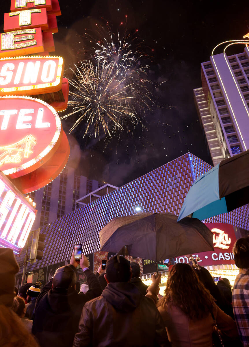 Revelers watch a fireworks and drone show above the Plaza on New Year’s Eve under a ligh ...