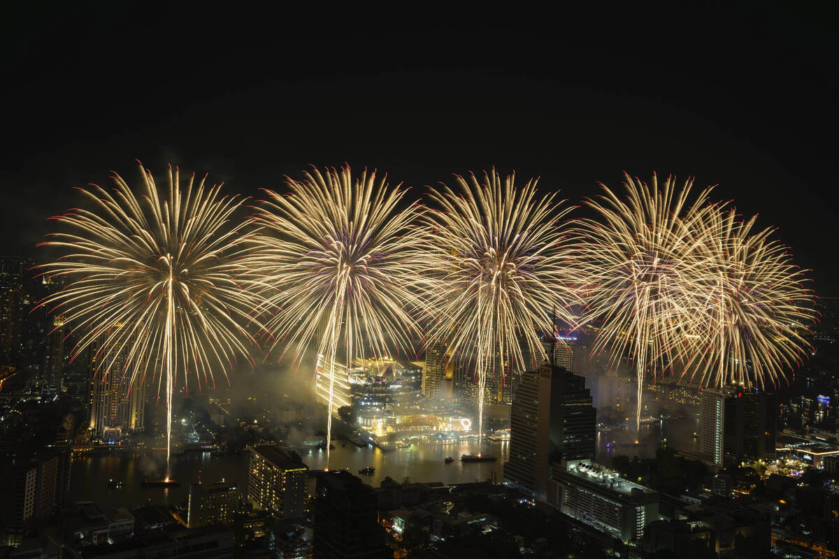 Fireworks explode over the Chao Phraya River during New Year celebrations in Bangkok, Thailand, ...