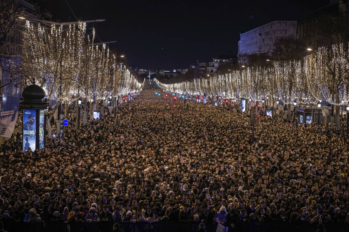 Revelers watch a sound and light show projected on the Arc de Triomphe as they celebrate the Ne ...