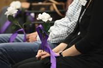People hold flowers with the names of domestic violence victims killed in the last year during ...