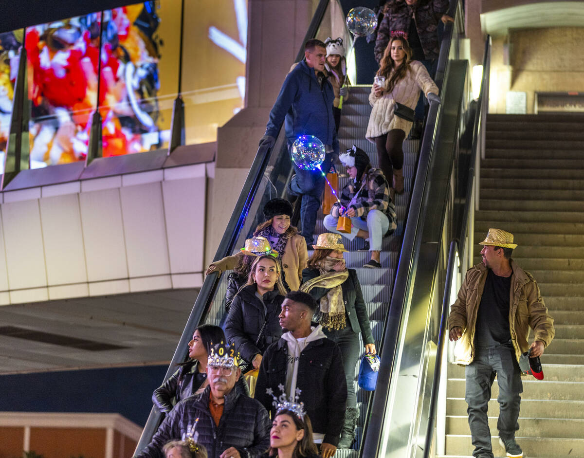 New Year’s Eve revelers move down an escalator near Fashion Show Mall along the Strip on ...