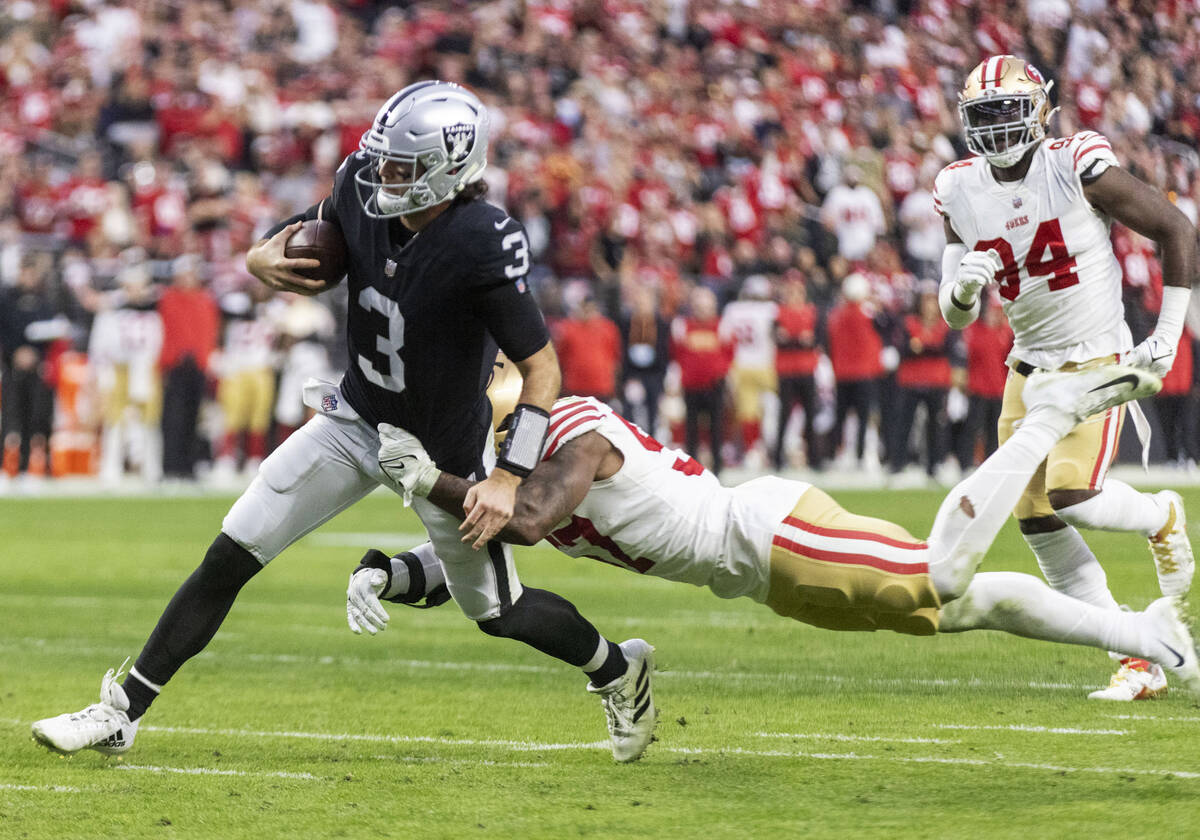 Raiders quarterback Jarrett Stidham (3) tries to shake a tackle from San Francisco 49ers lineba ...
