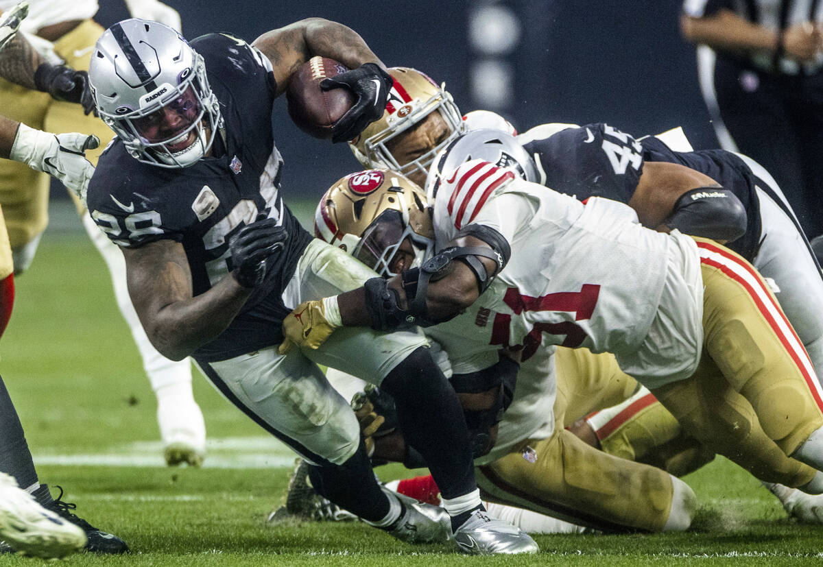 Raiders running back Josh Jacobs (28) battles for more yards against San Francisco 49ers lineba ...