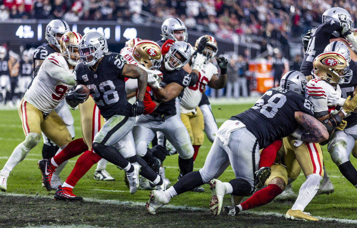 Raiders running back Josh Jacobs (28) scampers into the end zone past the San Francisco 49ers d ...