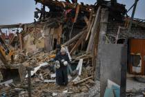 Local residents carry their belongings as they leave their home ruined in the Saturday Russian ...