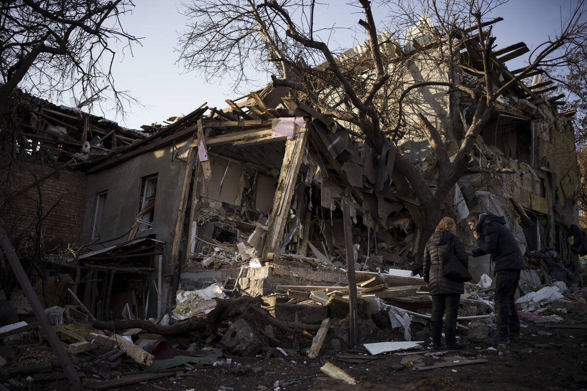 Serhii Kaharlytskyi, right, stands outside his home, destroyed after a Russian attack in Kyiv, ...
