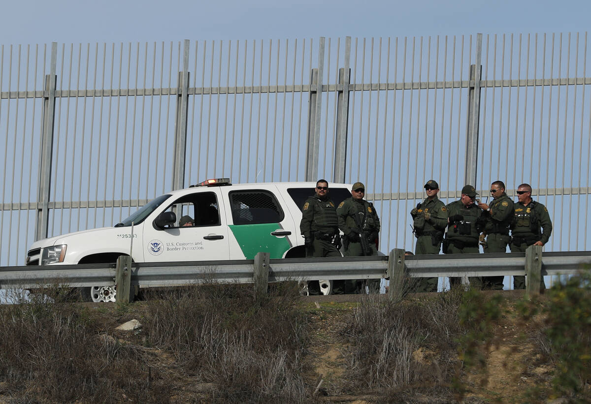 U.S. Border Patrol agents stand in front of a secondary fence in San Diego, California looking ...