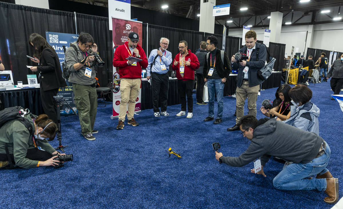 Attendees gather around a tiny robot being controlled by natural langage and voice commands by ...