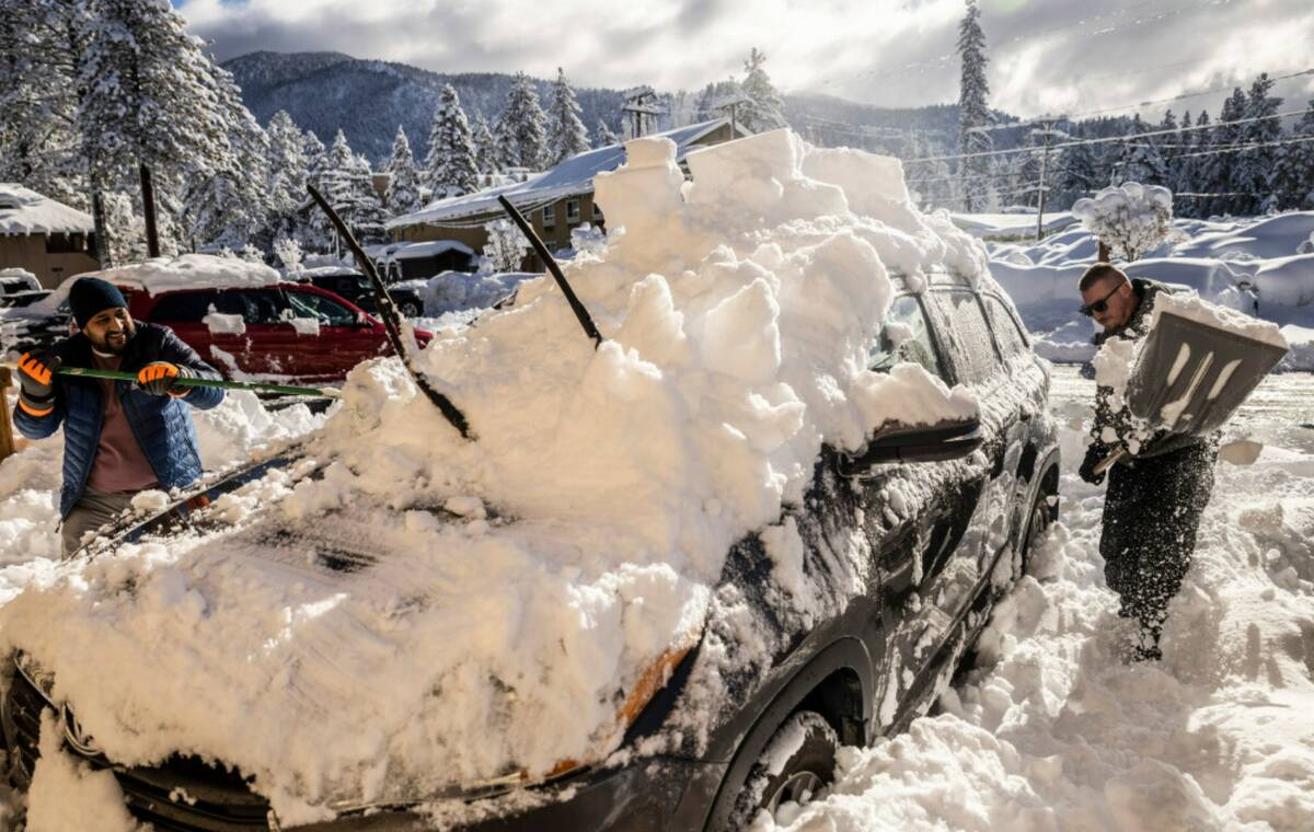 Bryon Wilson, right, helps Shobhit, last name withheld, left, remove snow accumulated on a vehi ...