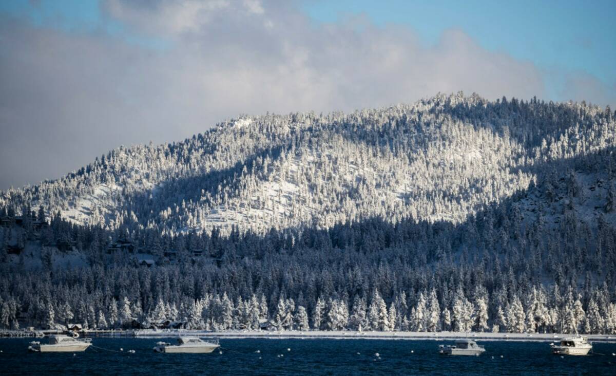 Moored boats are seen in Lake Tahoe as a coat of fresh snow is seen on a mountain the morning a ...