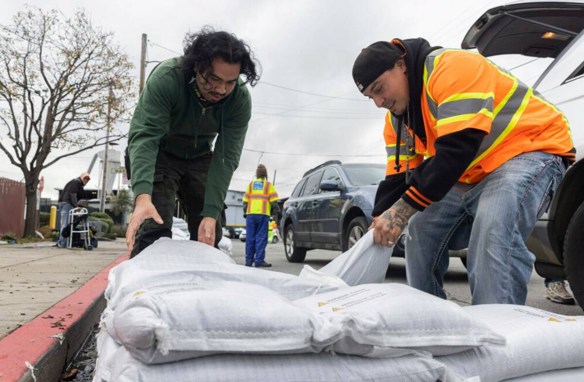 Fernando Bizarro, left, collects sandbags from an emergency distribution center to prepare for ...