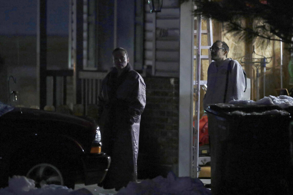 Neighbors watch as law enforcement officials work at a nearby Enoch, Utah, home where eight mem ...