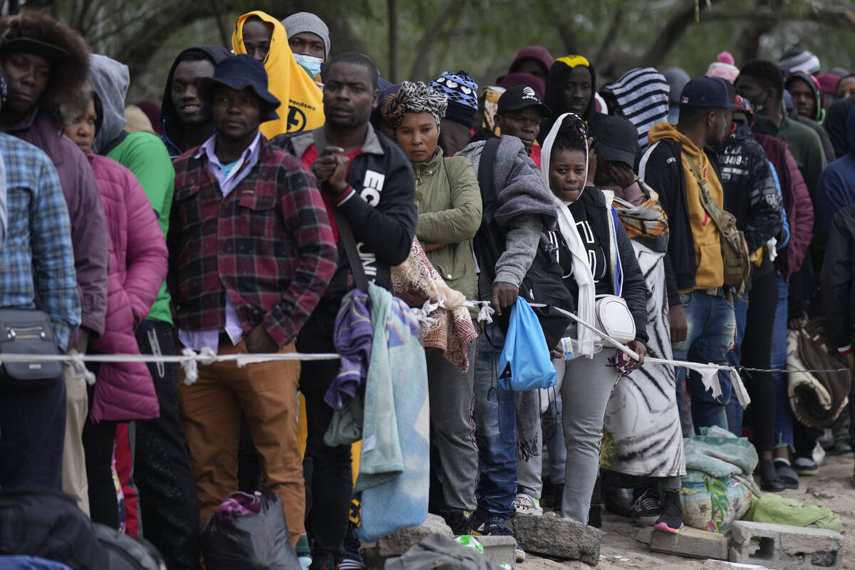 FILE - Haitian migrants who hope to apply for asylum in the U.S. wait to register their names o ...
