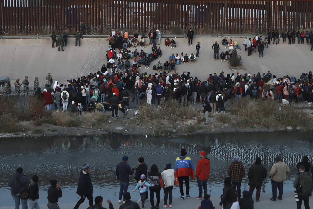 FILE - Migrants gather at a crossing into El Paso, Texas, as seen from Ciudad Juarez, Mexico, D ...