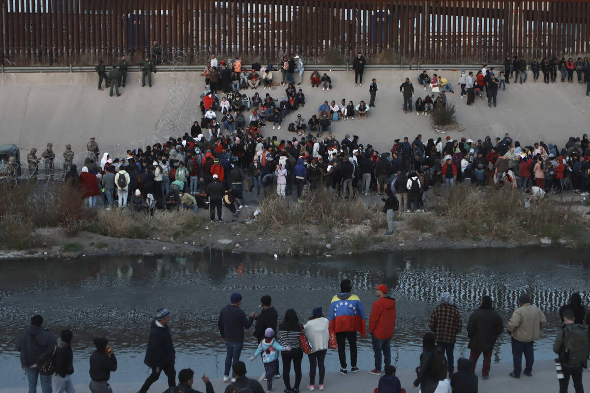 FILE - Migrants gather at a crossing into El Paso, Texas, as seen from Ciudad Juarez, Mexico, D ...