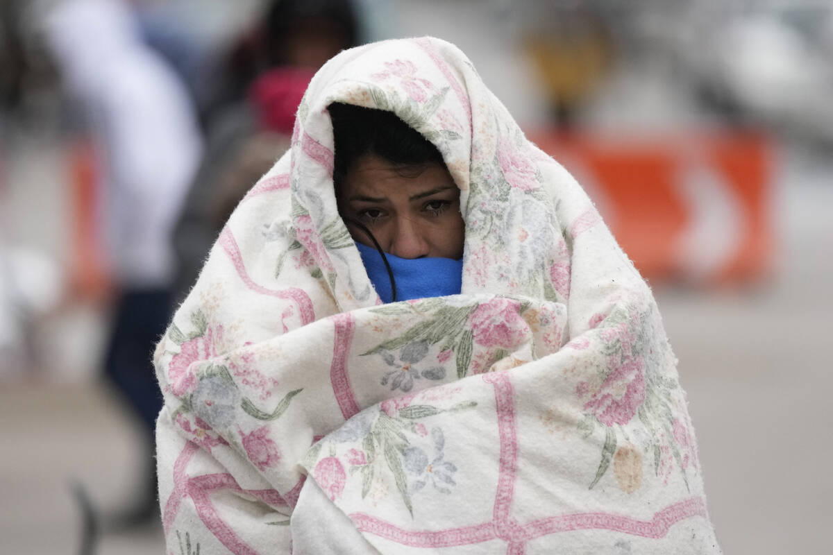 FILE - A migrant from Venezuela walks in the cold weather at a makeshift camp on the U.S.-Mexic ...