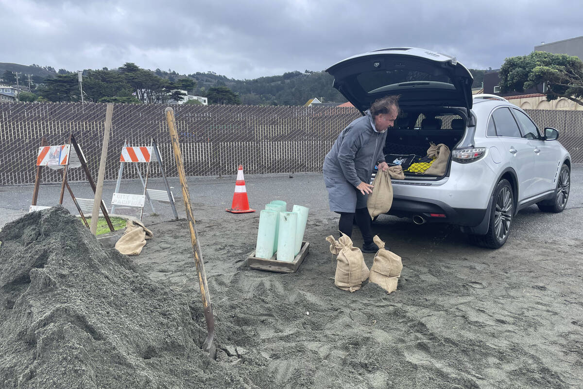 A man loads the back of his car with sandbags, Wednesday, Jan. 4, 2023, in Pacifica, Calif. A m ...