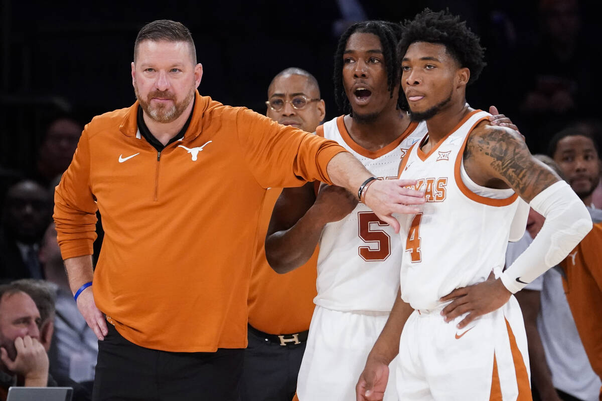 Texas head coach Chris Beard, left, meets with Tyrese Hunter (4) and Marcus Carr (5) at the ben ...