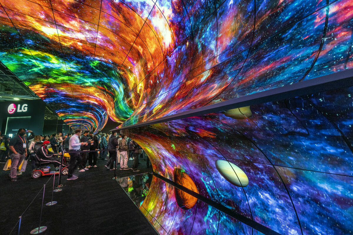 Attendees stream past a dynamic LG projection system display into the central hall during the o ...