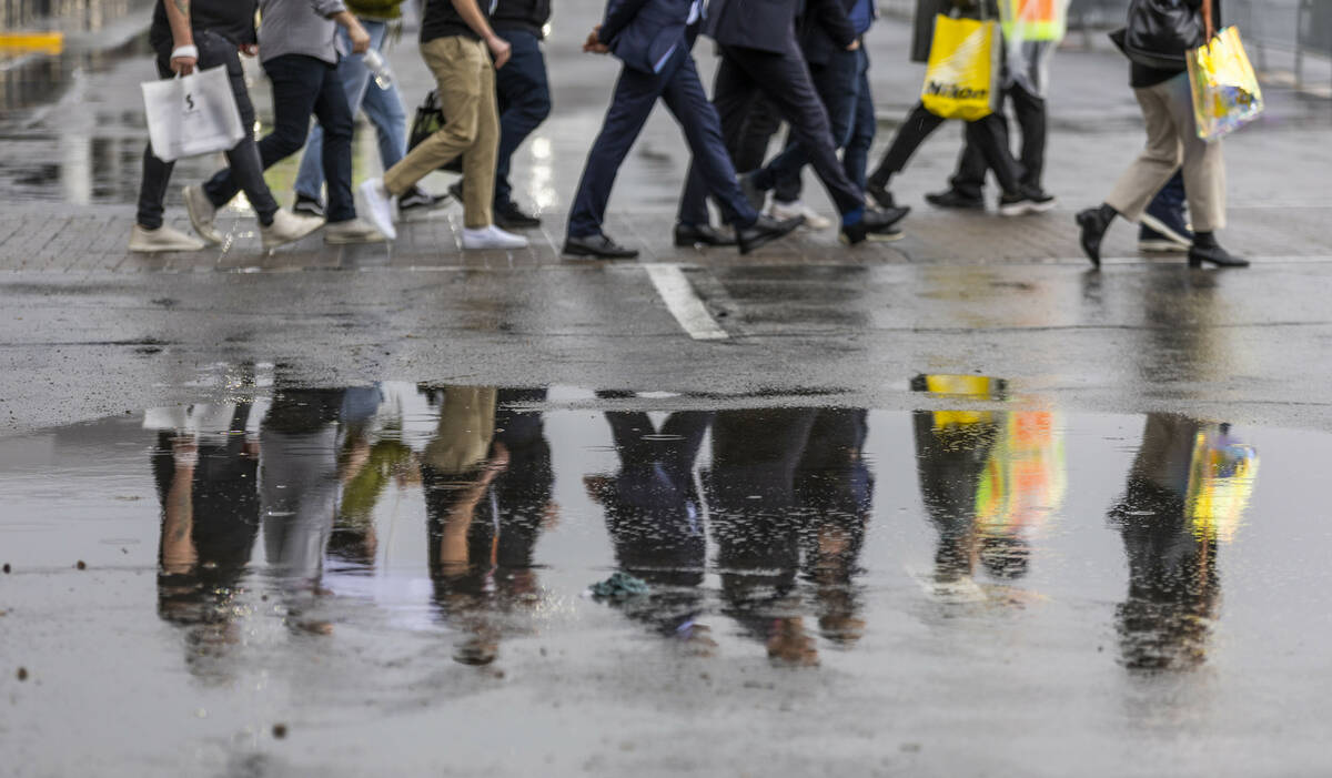 Attendees walk to more exhibits the rain outside during the opening day of CES 2023 at the Las ...
