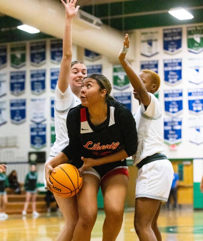 Liberty High's Daisha Peavy (12) drives past between Green Valley's Kyra Willey (25) and Thai B ...