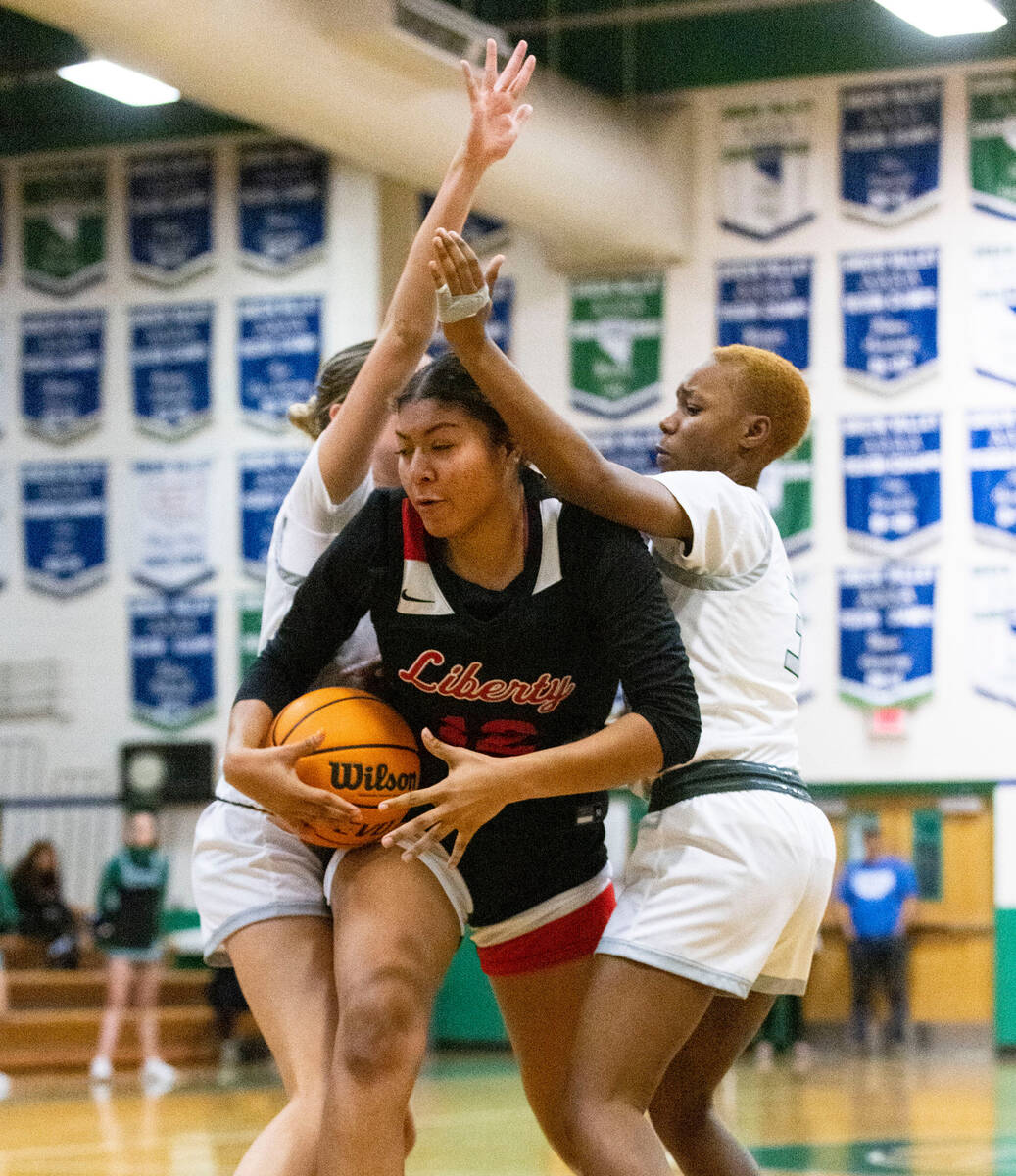 Liberty High's Daisha Peavy (12) secures the ball as she drives past between Green Valley's Kyr ...