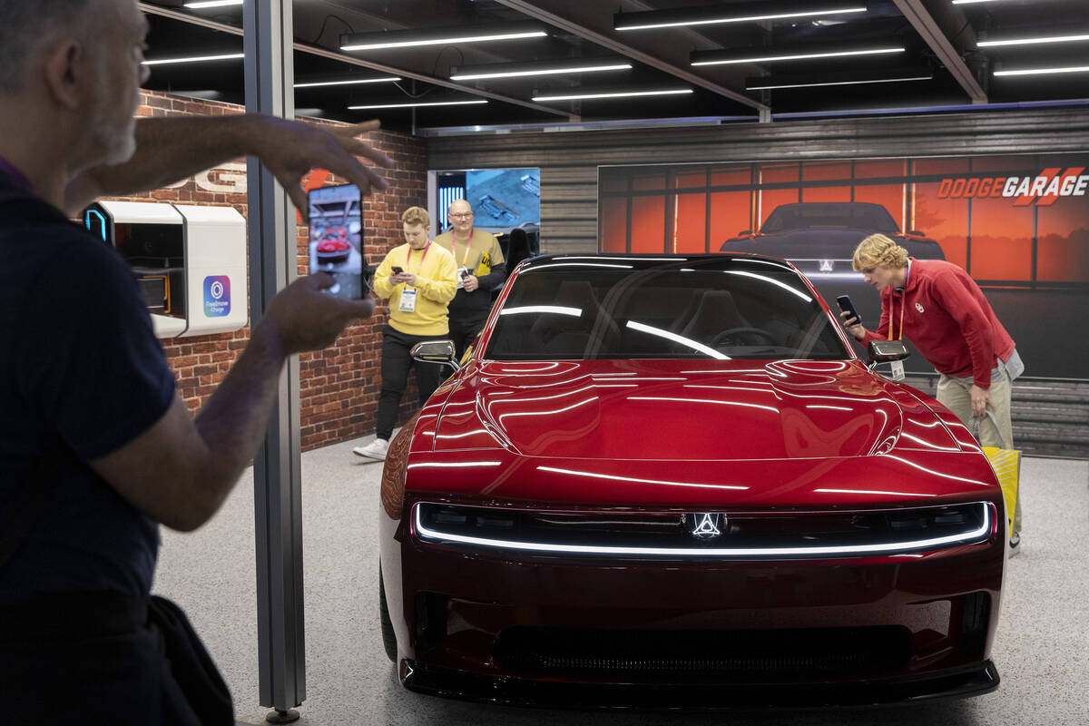 Attendees view an electric Dodge Charger in the Stellantis booth during the CES tech show at th ...