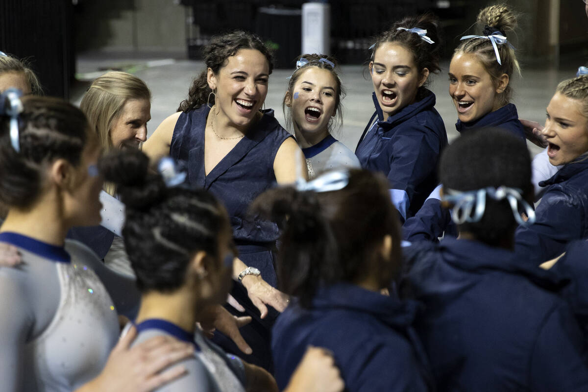 University of North Carolina competitors cheer together after competing in uneven bars during s ...