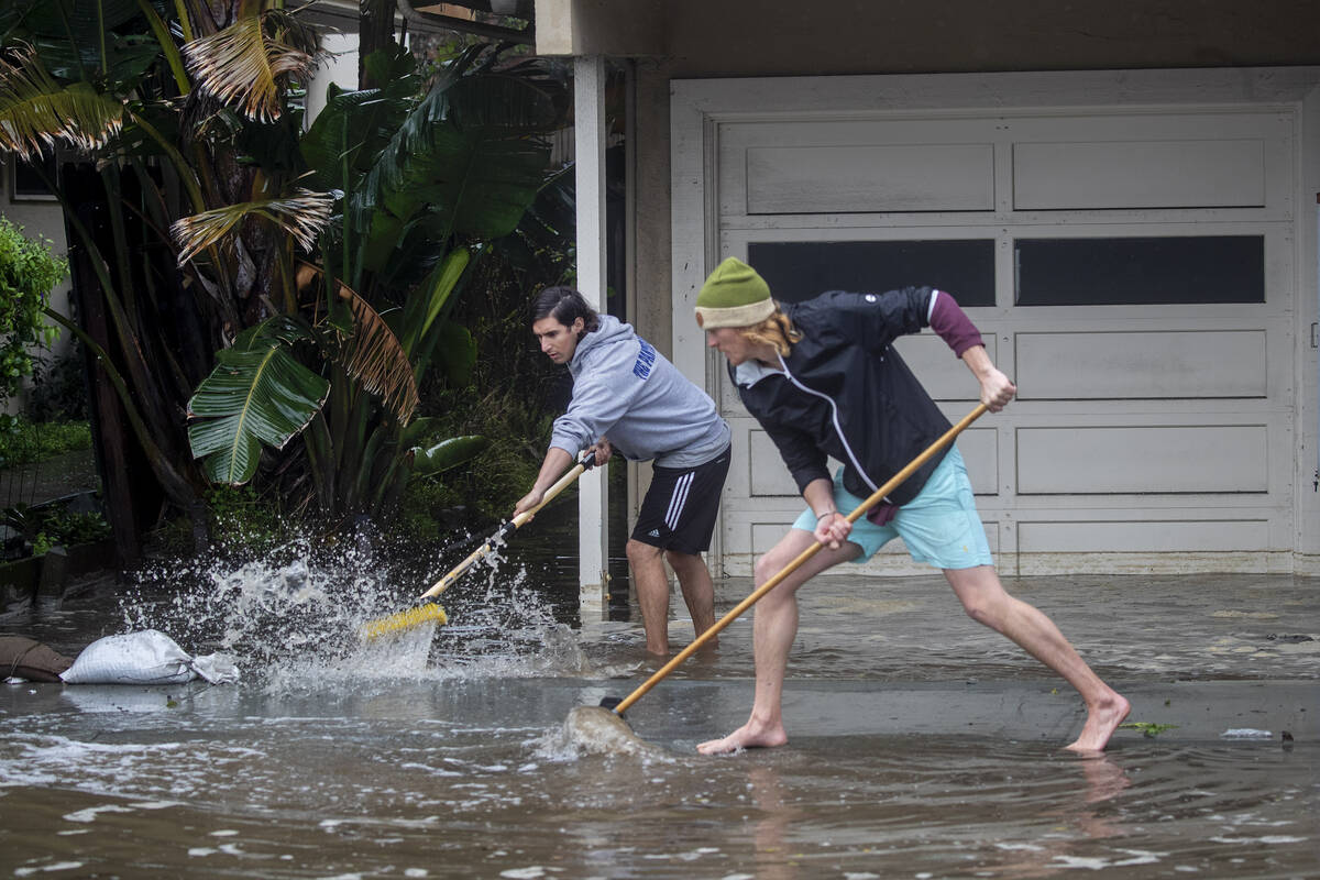 Evan Sousa, left, gets help from Calvin Drake pushing water out of his flooded apartment on Pal ...