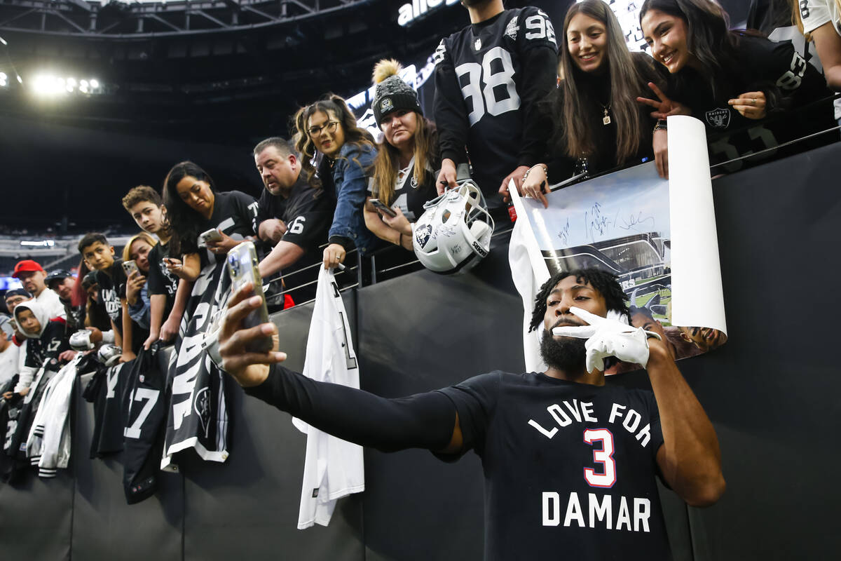 Raiders cornerback Nate Hobbs takes pictures with fans before an NFL game at Allegiant Stadium ...