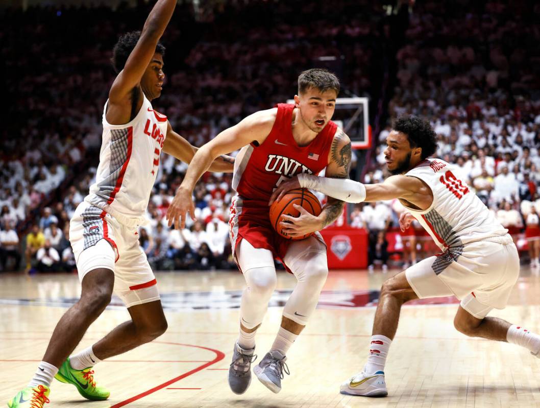 UNLV guard Jordan McCabe drives between New Mexico's Donovan Dent, left and Jaelen House during ...