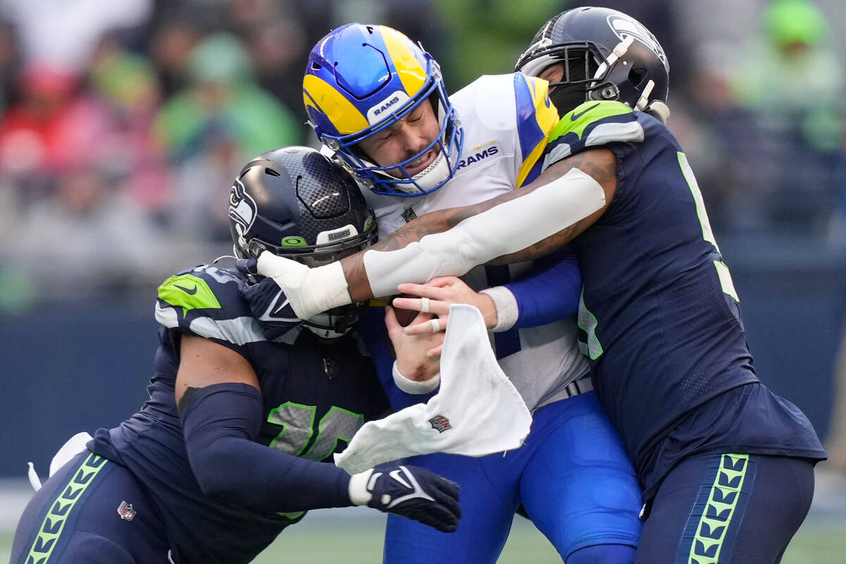Los Angeles Rams quarterback Baker Mayfield, center, is tackled by Seattle Seahawks linebackers ...