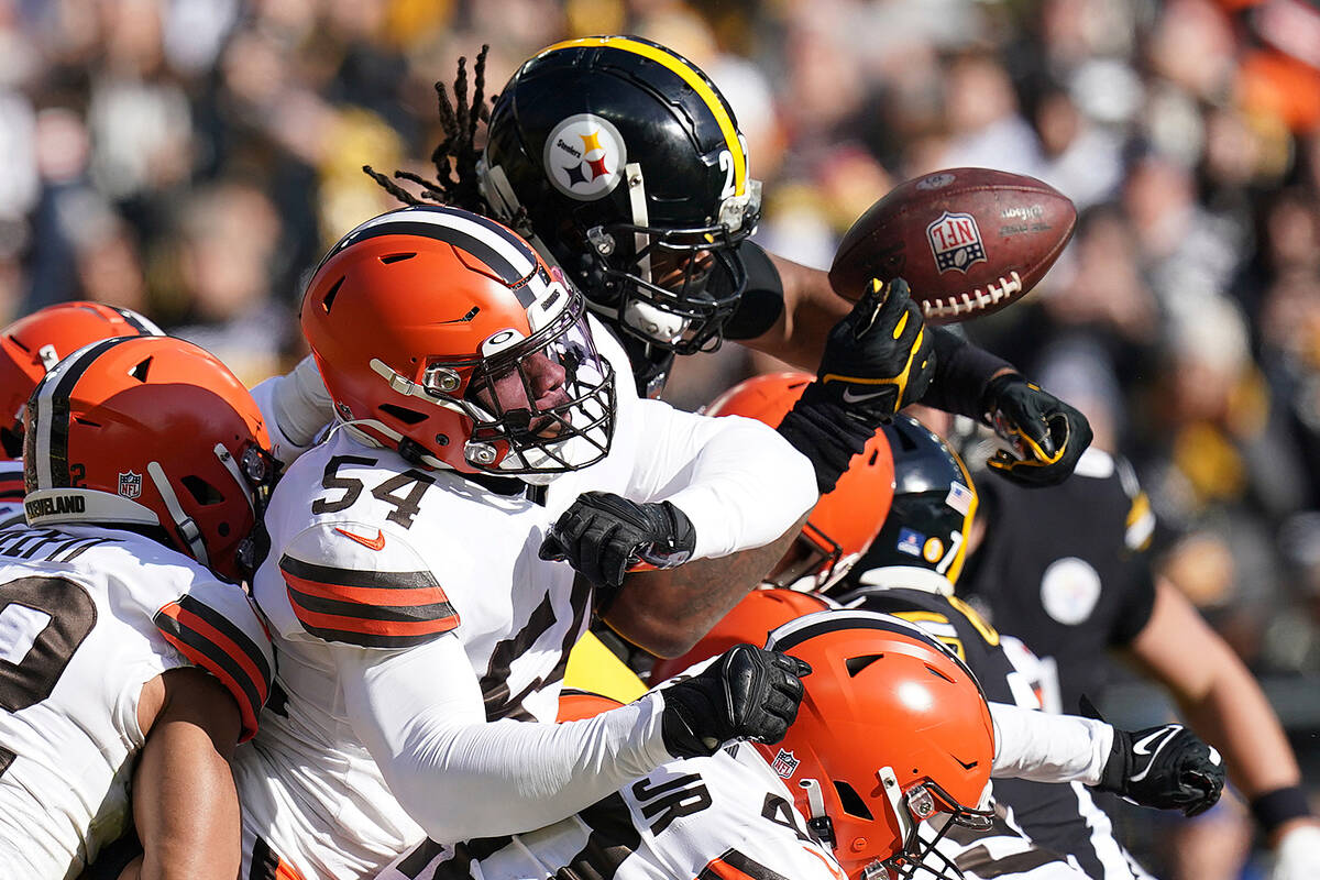 Pittsburgh Steelers running back Najee Harris (22), top, fumbles after being hit by Cleveland B ...