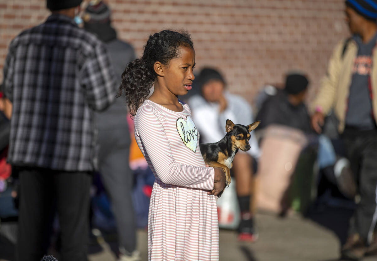 A migrant child holds her dog while camping outside the Sacred Heart Church in downtown El Paso ...