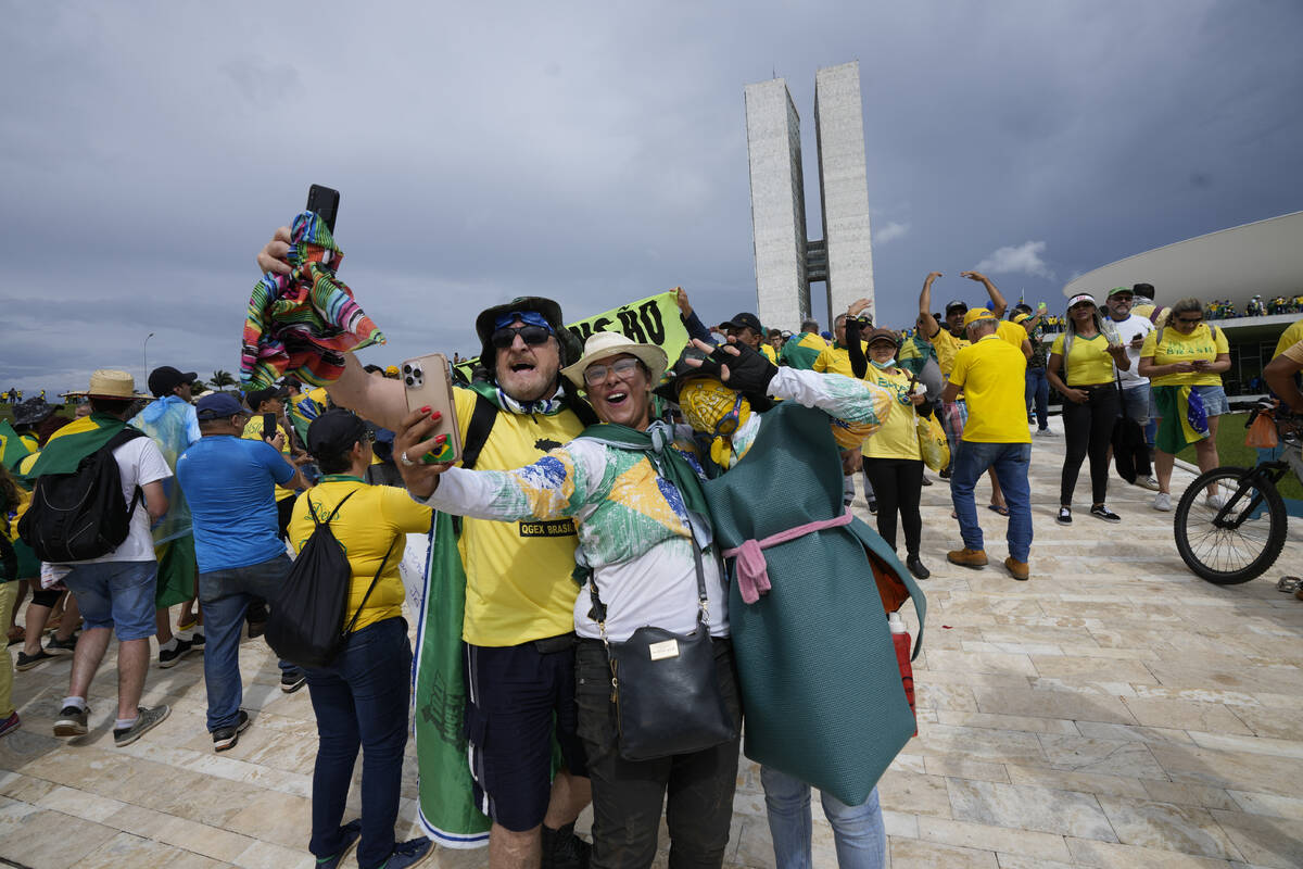 Protesters, supporters of Brazil's former President Jair Bolsonaro, take selfies as they storm ...