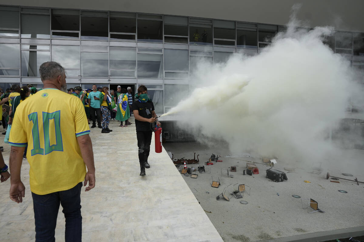 A protester, supporter of Brazil's former President Jair Bolsonaro, empties a fire extinguisher ...