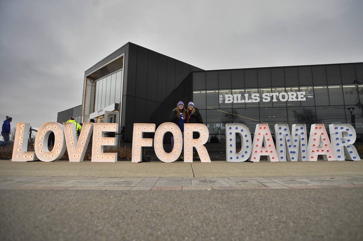 Fans stand for photographs by a sign in support of Buffalo Bills safety Damar Hamlin outside Hi ...