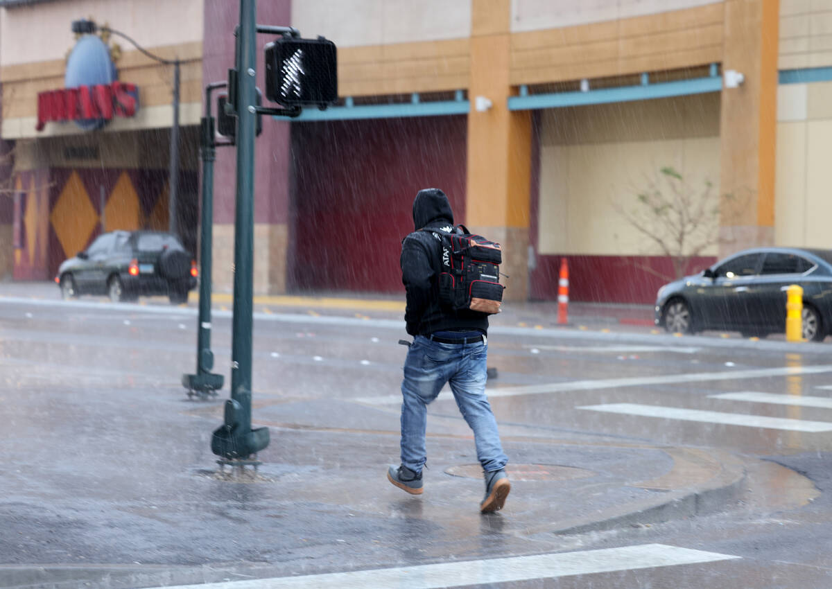 A pedestrian runs through the rain at Las Vegas Boulevard and Ogden Avenue in Las Vegas Tuesday ...