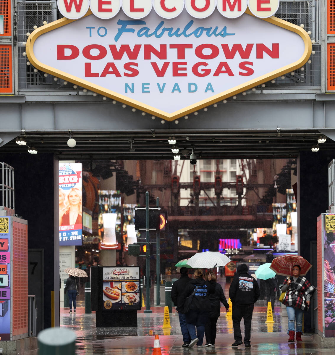 People walk in the rain on Fremont Street near Las Vegas Boulevard in Las Vegas Tuesday, Jan. 1 ...