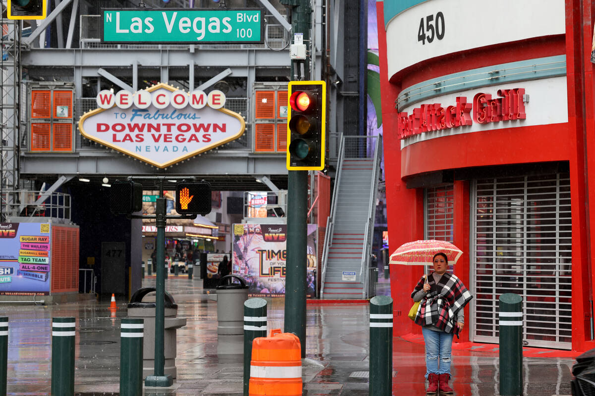 A pedestrian waits to cross the street on Fremont Street at Las Vegas Boulevard in Las Vegas Tu ...