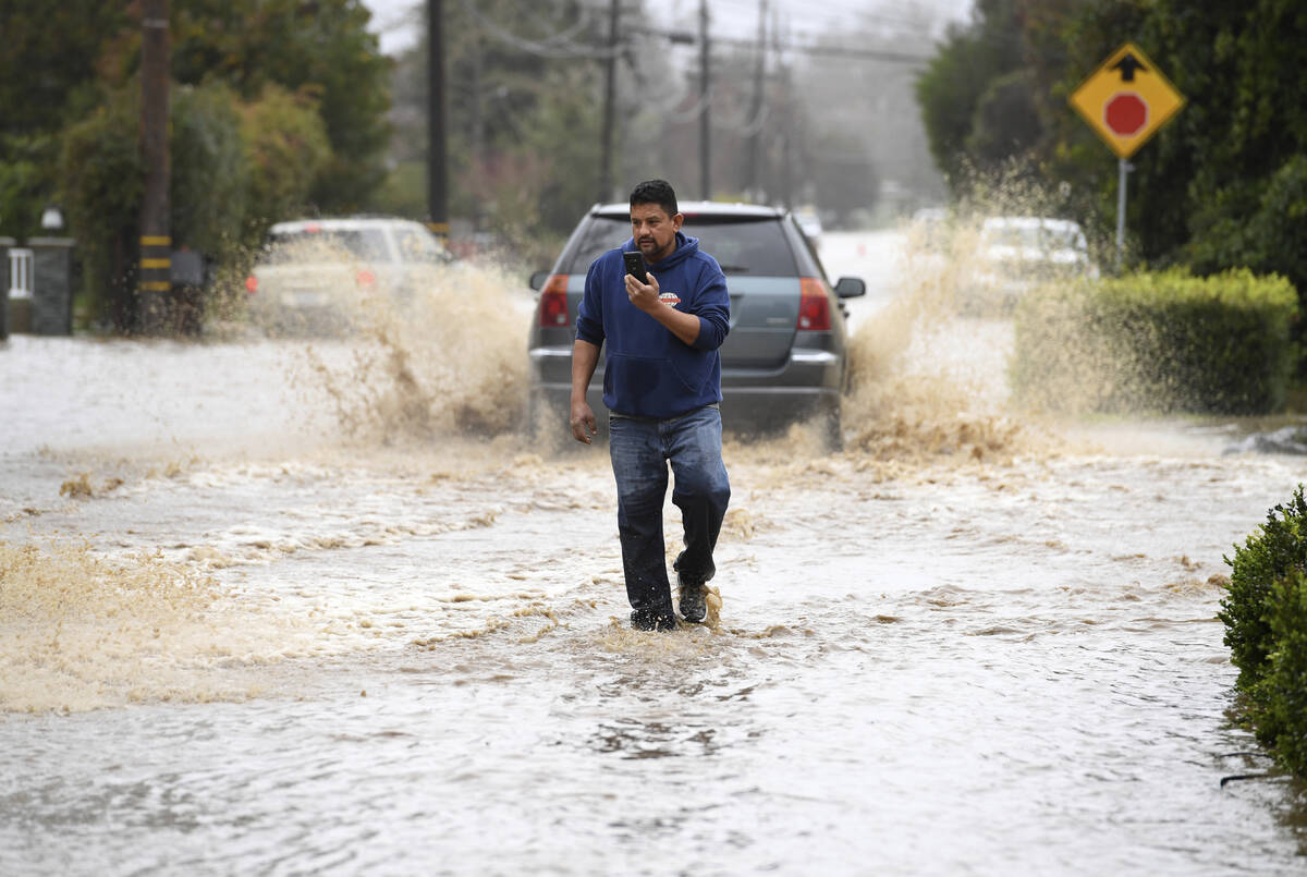 A resident walks along College Road after the area was flooded during a recent storm in Watsonv ...