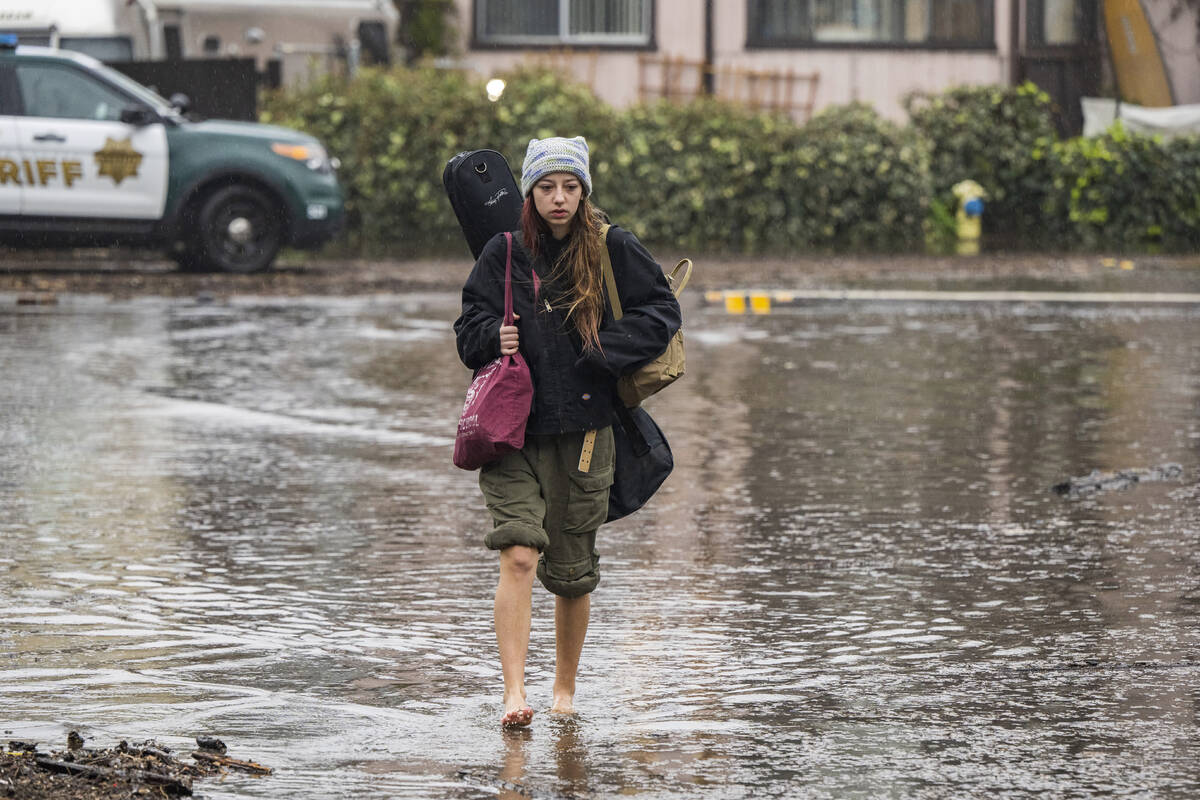 Naia Skogerson evacuates from her house as floodwaters rise in the Rio Del Mar neighborhood of ...