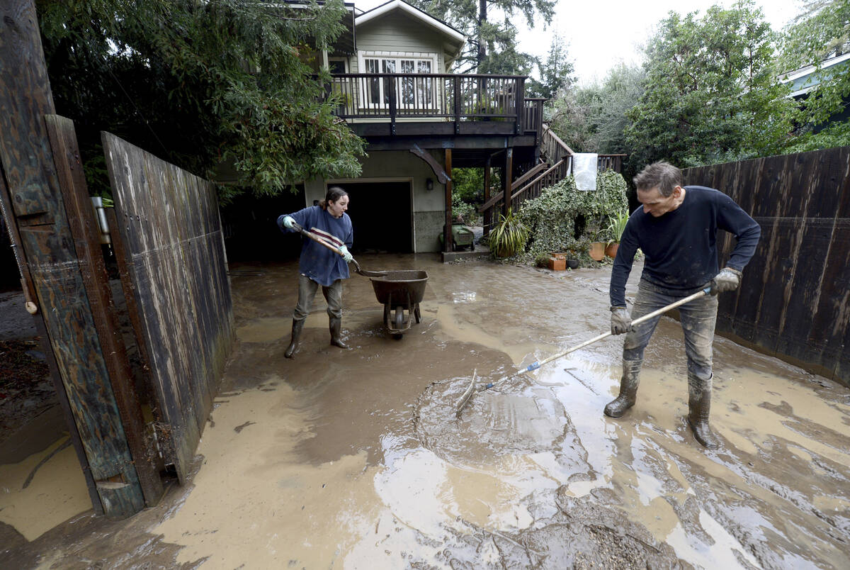 Maisie Russo, of Felton, helps home owner Tom Fredericks, of Felton, after heavy rains swelled ...