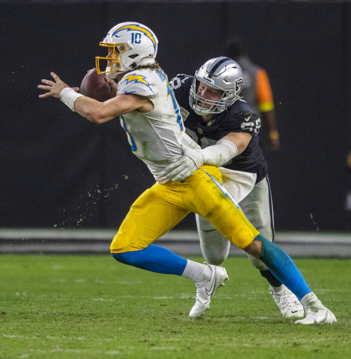 Raiders defensive end Maxx Crosby (98) wraps up Los Angeles Chargers quarterback Justin Herbert ...