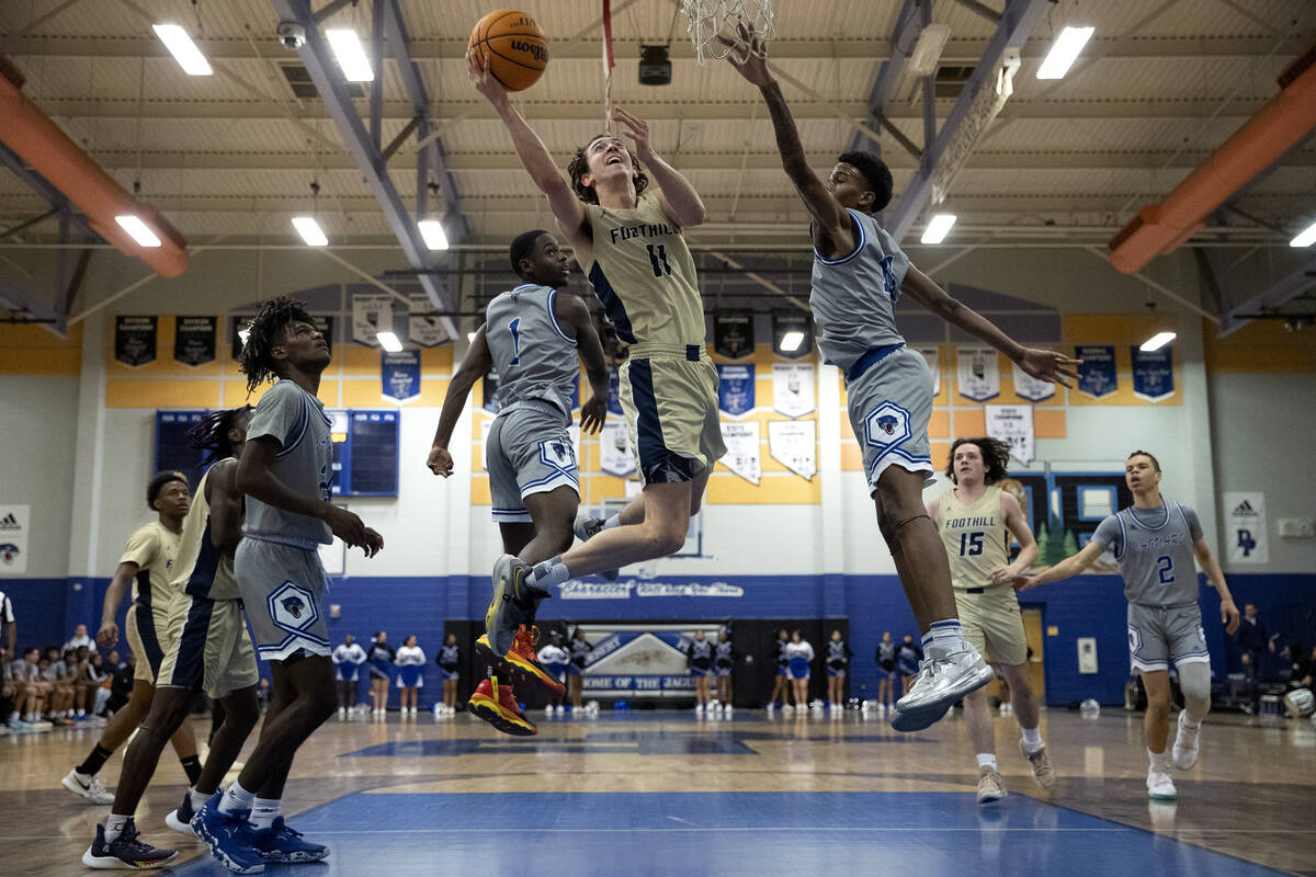 Foothill’s Zakary Abdalla (11) shoots against Desert Pines’ Kameron Ricks (1) and ...